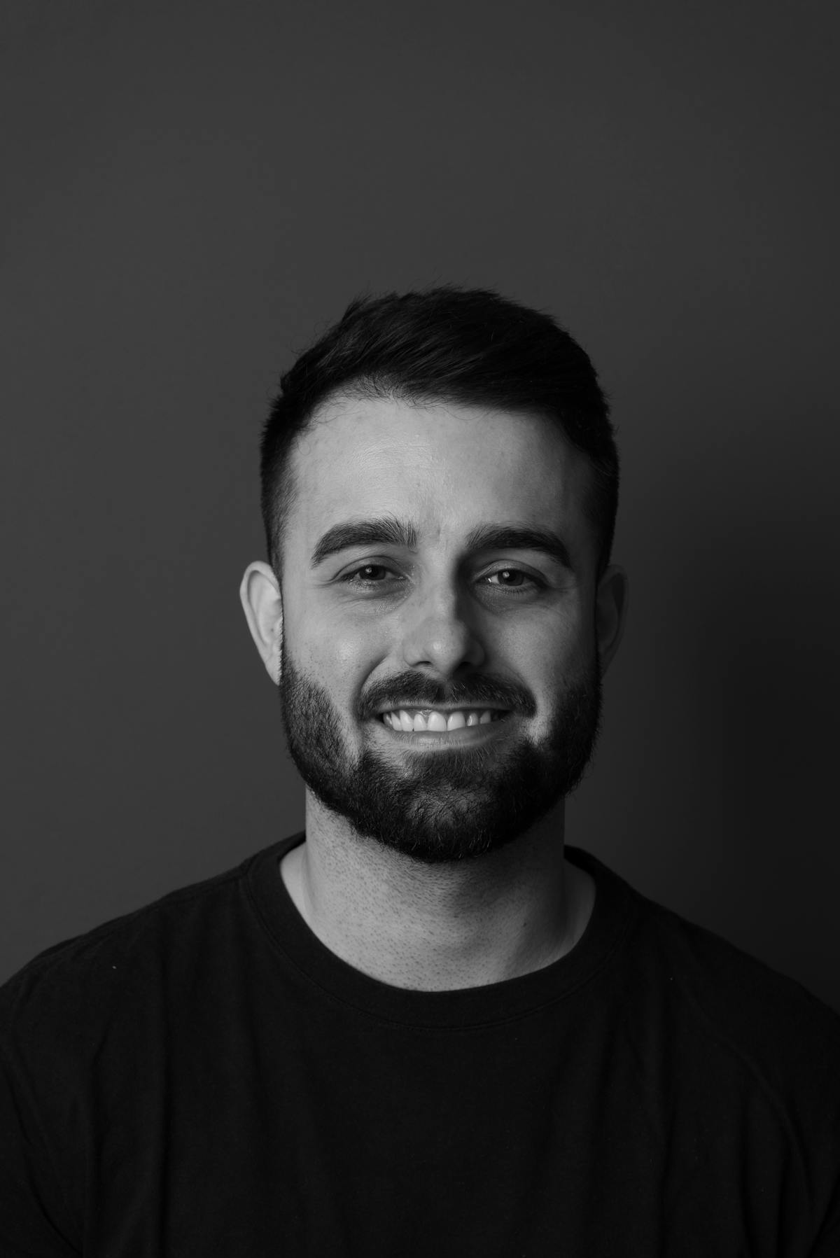 Black-and-white portrait of a smiling man with a short beard